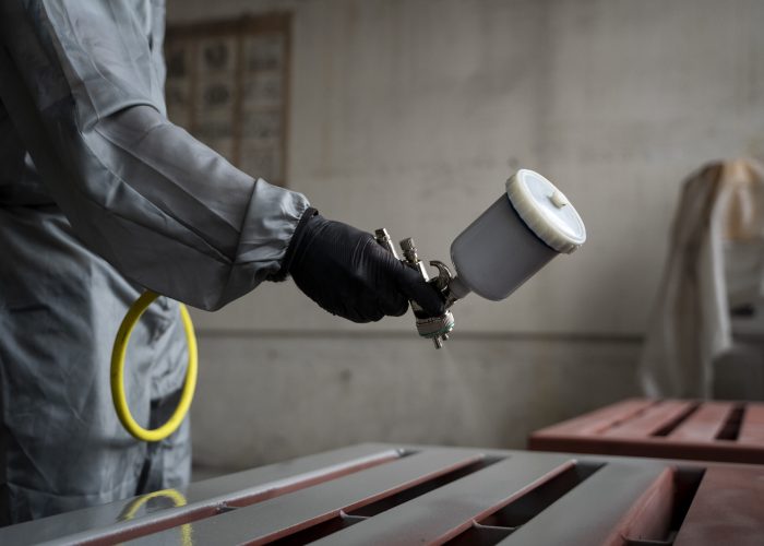 side-view-worker-spraying-powder-paint-from-gun